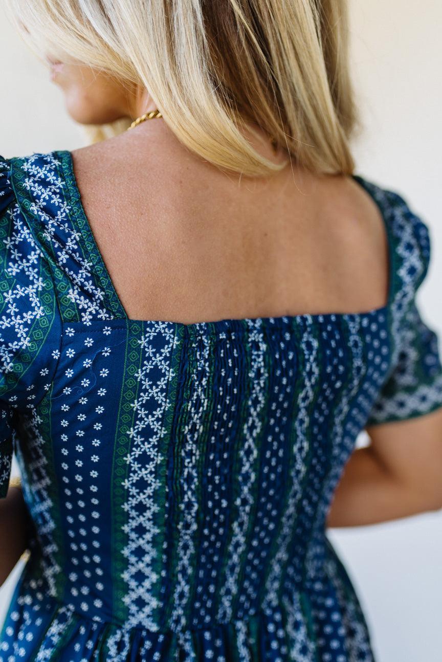 Woman wearing a blue patterned dress with a white background