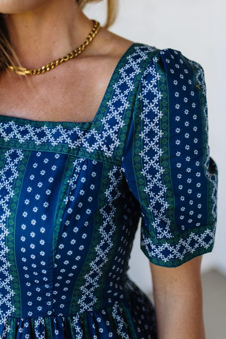 Close-up of a person wearing a blue and green patterned dress with a white background