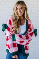 Woman wearing a colorful striped cardigan against a white brick wall