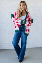 Woman wearing a red and green striped sweater with a white brick wall background