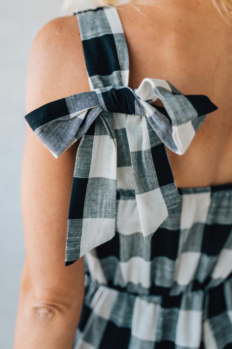 Black and white checkered jumpsuit with bow detail strap on a plain background