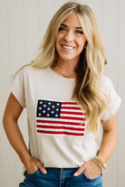 Woman wearing a white t-shirt with an American flag design against a plain background