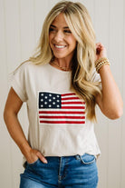 Woman wearing a white t-shirt with an American flag design against a plain background