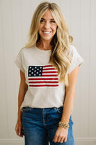 Woman wearing a white t-shirt with an American flag design and blue jeans.