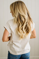 Person wearing a white t-shirt and blue jeans with long blonde hair, standing against a neutral background.