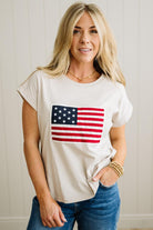 Woman wearing a white t-shirt with an American flag design against a plain background
