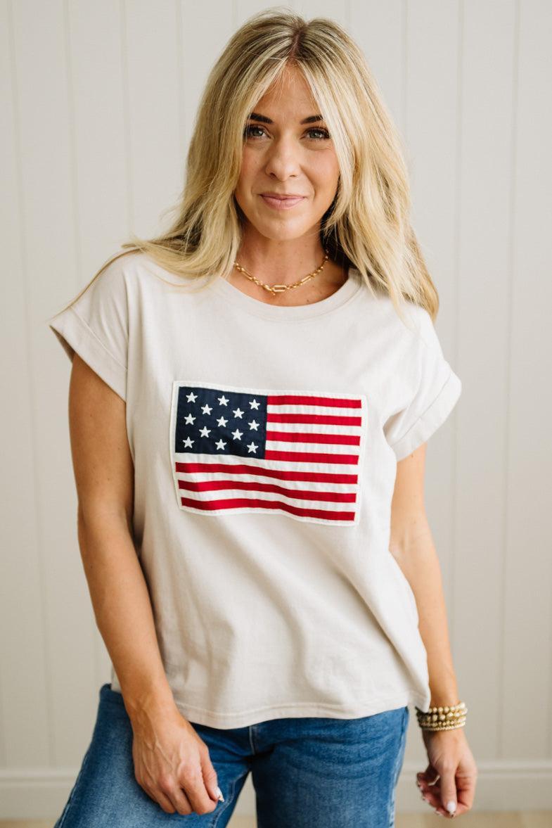Woman wearing a white t-shirt with an American flag design against a plain background