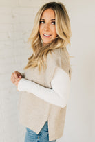 BLONDE WOMAN WEARING AN OVERSIZED SWEATER VEST WITH SIDE SLIT