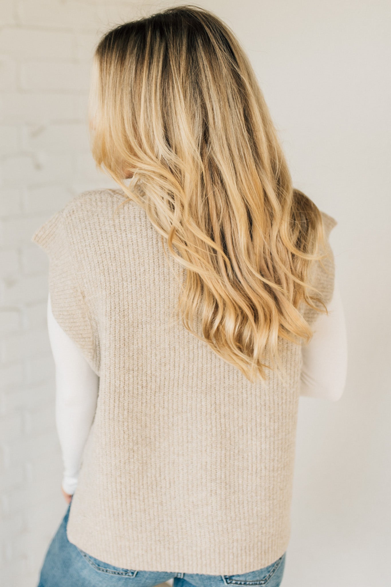 BLONDE WOMAN WEARING AN OVERSIZED SWEATER VEST WITH SIDE SLIT