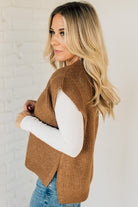 BLONDE WOMAN WEARING AN OVERSIZED SWEATER VEST WITH SIDE SLIT