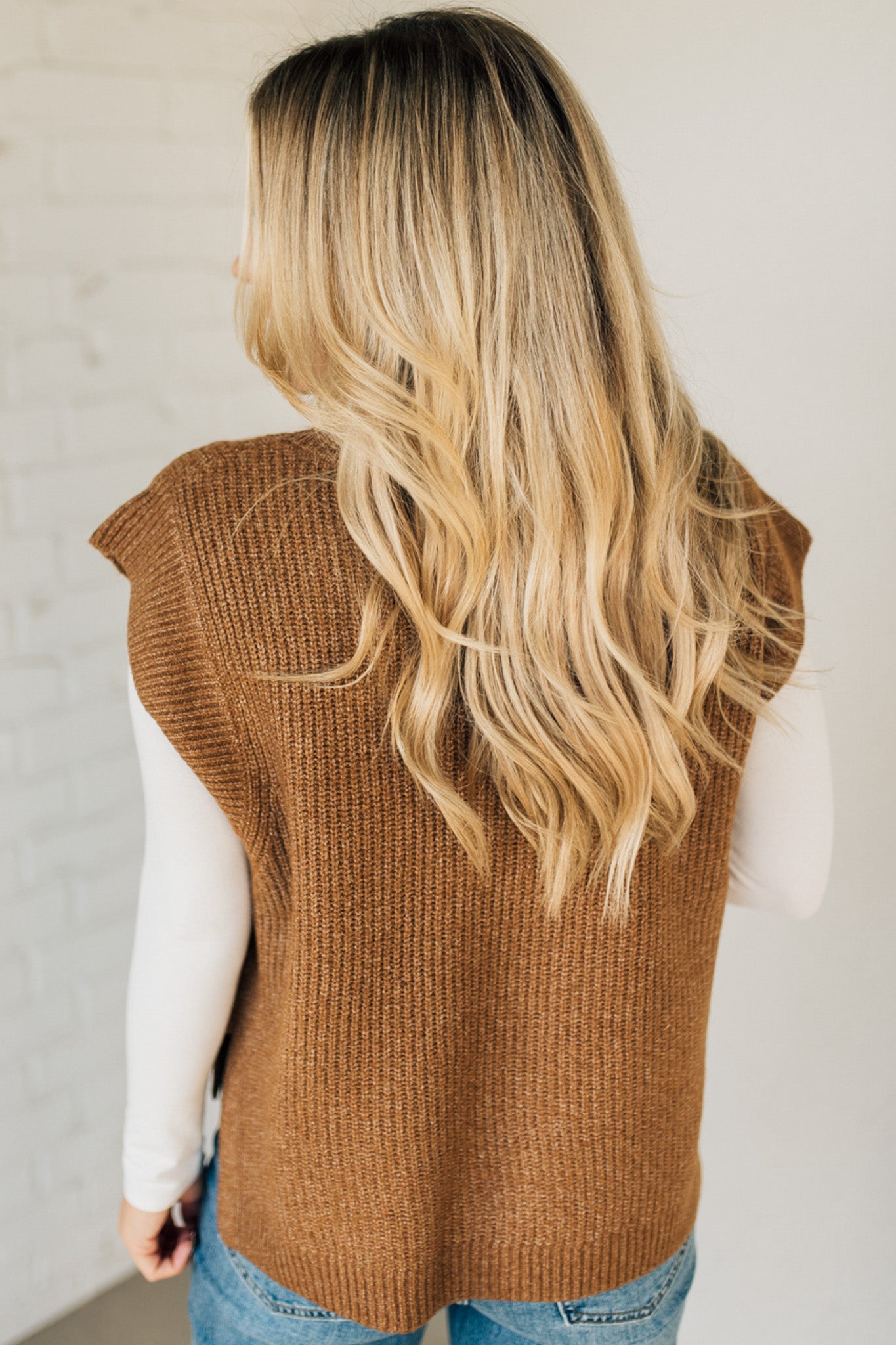 BLONDE WOMAN WEARING AN OVERSIZED SWEATER VEST WITH SIDE SLIT