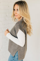 BLONDE WOMAN WEARING AN OVERSIZED SWEATER VEST WITH SIDE SLIT