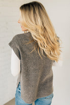 BLONDE WOMAN WEARING AN OVERSIZED SWEATER VEST WITH SIDE SLIT