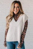 BLONDE WOMAN WEARING AN OVERSIZED SWEATER VEST WITH SIDE SLIT