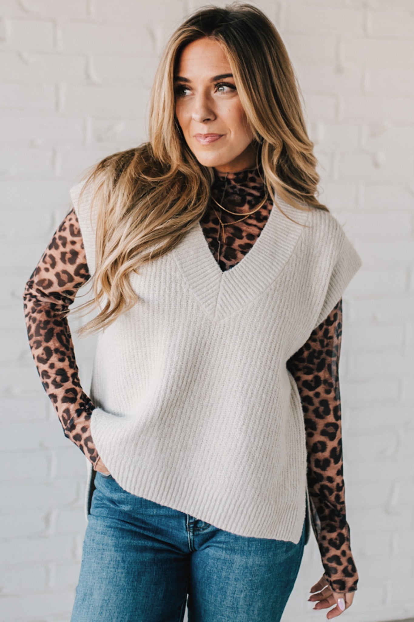 BLONDE WOMAN WEARING AN OVERSIZED SWEATER VEST WITH SIDE SLIT