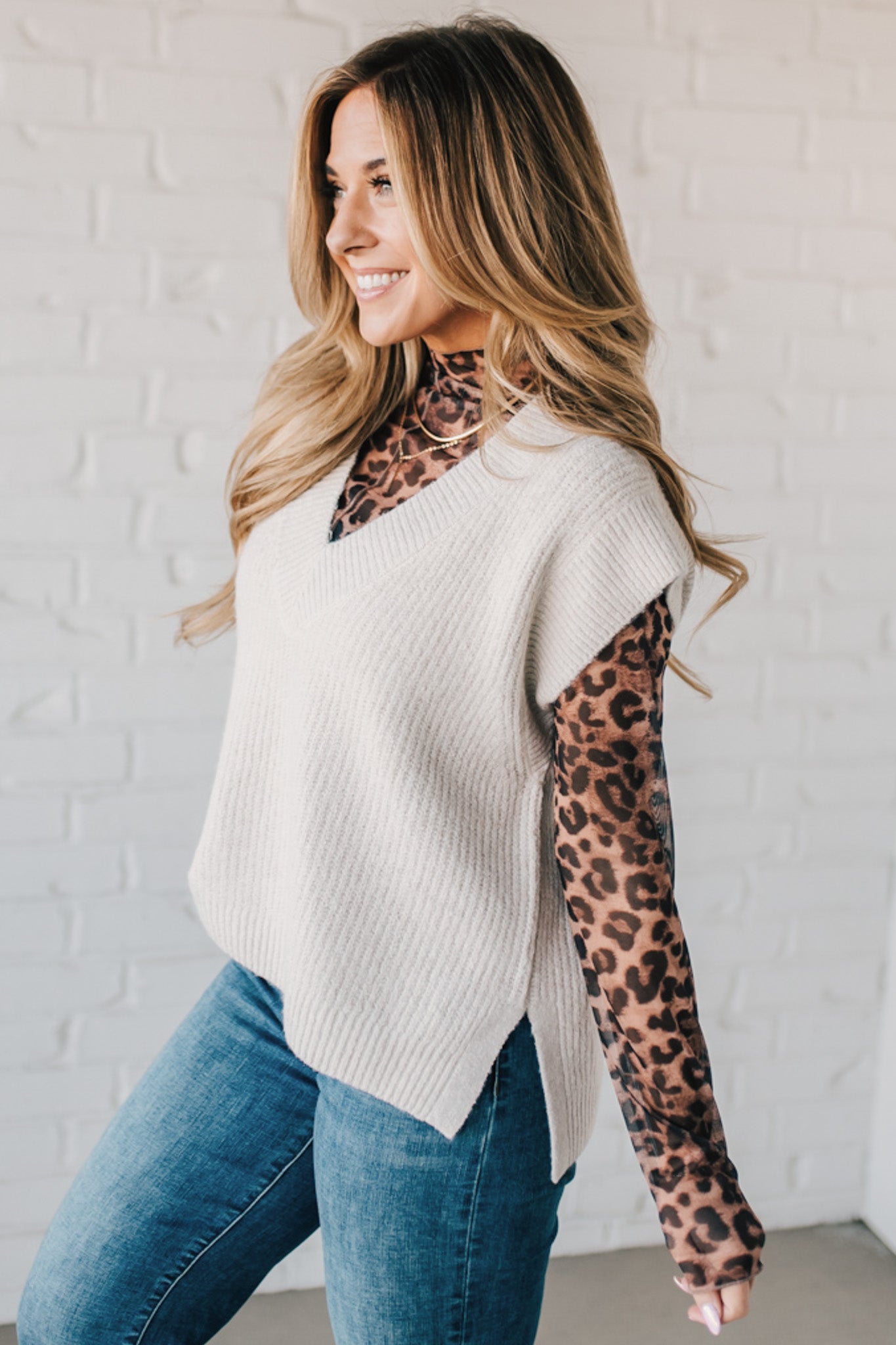 BLONDE WOMAN WEARING AN OVERSIZED SWEATER VEST WITH SIDE SLIT