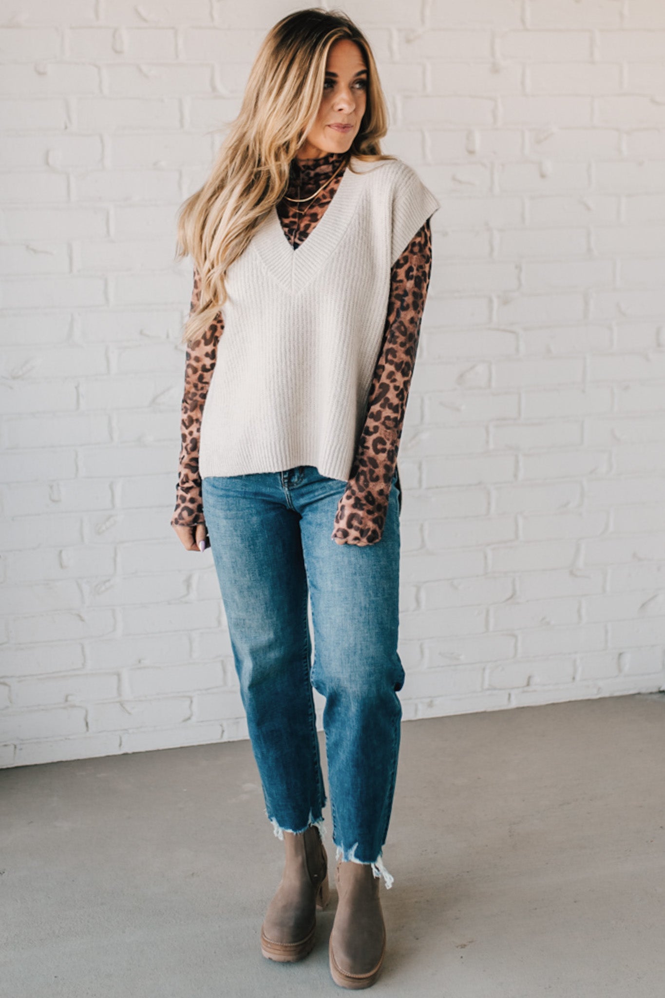 BLONDE WOMAN WEARING AN OVERSIZED SWEATER VEST WITH SIDE SLIT