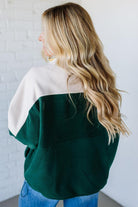 Person wearing a green and white color-blocked sweater against a white background