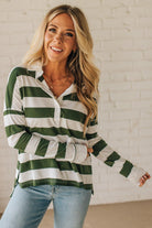 Woman wearing a green and white striped shirt against a white brick wall.