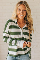 Woman wearing a green and white striped shirt against a white brick wall.