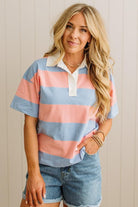 Woman wearing a colorful striped shirt and denim shorts against a neutral background
