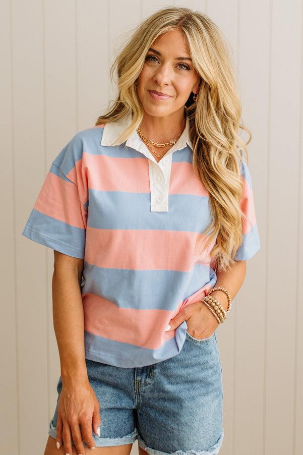 Woman wearing a colorful striped shirt and denim shorts against a neutral background