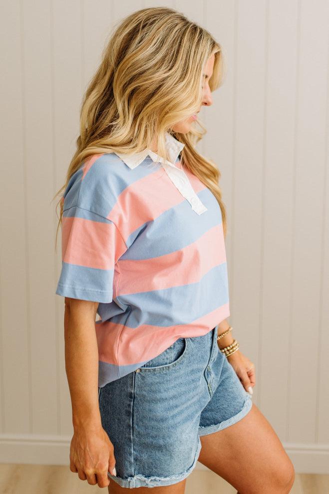 Woman wearing a colorful striped shirt and denim shorts against a neutral background