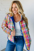 Woman wearing a colorful quilted jacket with a white background