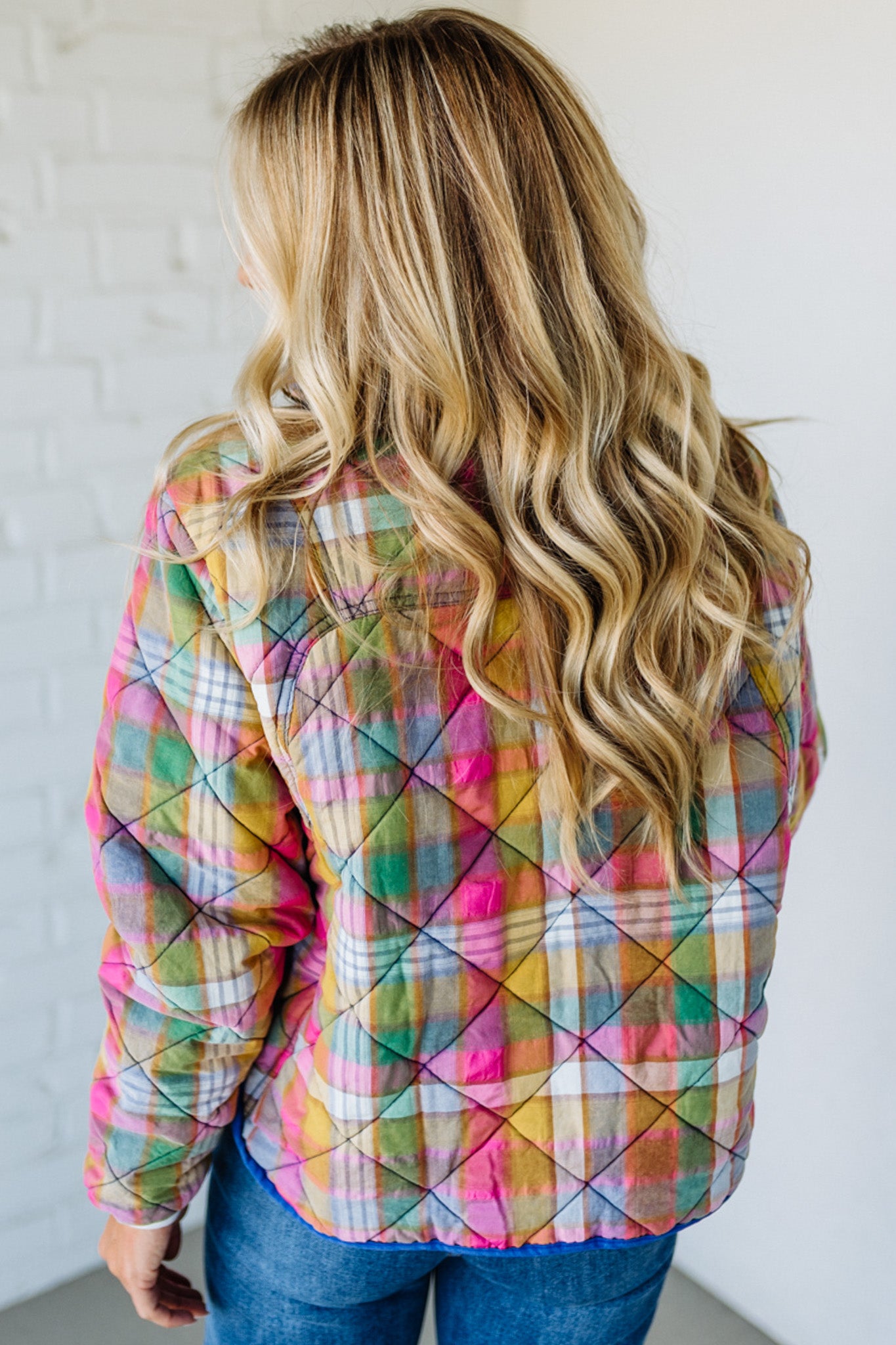 Person wearing a colorful quilted jacket with a plain background