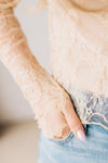 Blonde woman in blue jeans wearing a long sleeve mesh lace top with merrow hem.