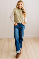 BLONDE WOMAN WEARING A MOCK NECK,  FRONT BUTTON DETAILED, WITH CAP SLEEVES AND STRIPES. STANDING IN A WELL LIT STUDIO.