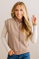 BLONDE WOMAN WEARING A MOCK NECK,  FRONT BUTTON DETAILED, WITH CAP SLEEVES AND STRIPES. STANDING IN A WELL LIT STUDIO.