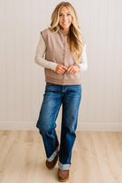BLONDE WOMAN WEARING A MOCK NECK,  FRONT BUTTON DETAILED, WITH CAP SLEEVES AND STRIPES. STANDING IN A WELL LIT STUDIO.