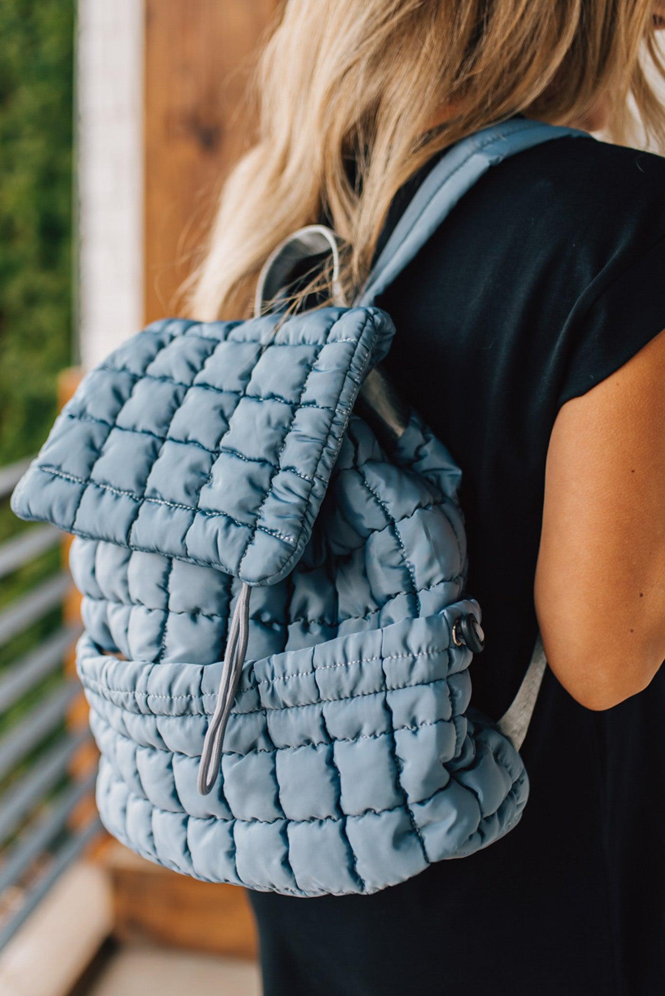 Blonde woman wearing a Blue Quilted Puffer Design Backpack with Easy Wipe Nylon Exterior.