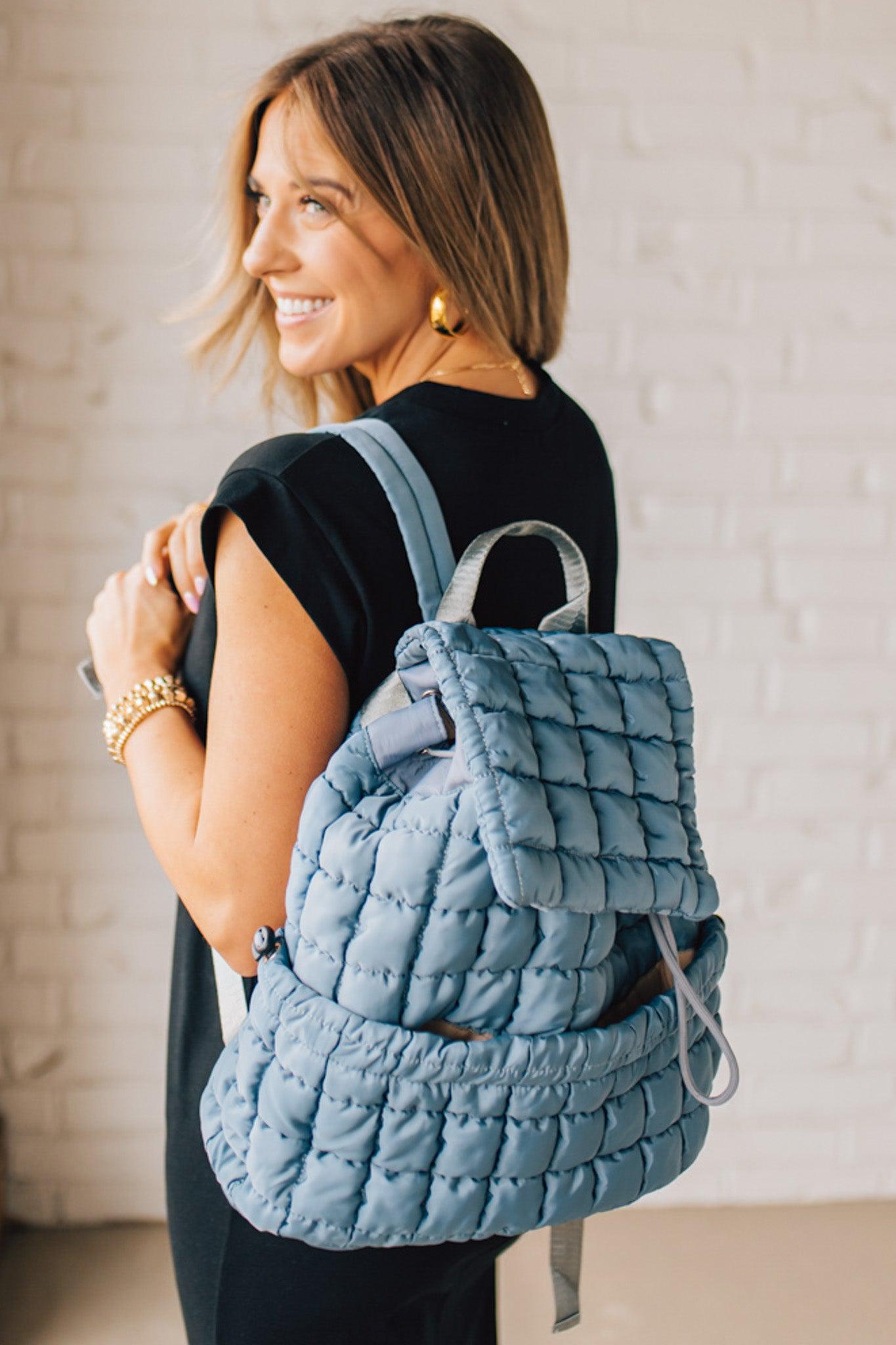 Blonde woman wearing a Blue Quilted Puffer Design Backpack with Easy Wipe Nylon Exterior.