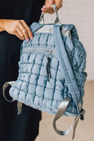 Blonde woman wearing a Blue Quilted Puffer Design Backpack with Easy Wipe Nylon Exterior.