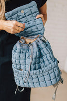 Blonde woman wearing a Blue Quilted Puffer Design Backpack with Easy Wipe Nylon Exterior.