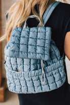 Blonde woman wearing a Blue Quilted Puffer Design Backpack with Easy Wipe Nylon Exterior.