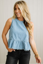 Woman wearing a light blue sleeveless top with ruffled hem against a neutral background