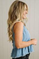 Woman wearing a denim sleeveless top against a neutral background