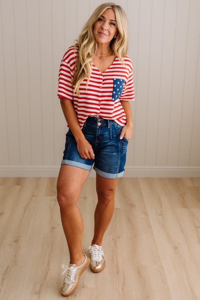 Woman wearing a red and white striped shirt with blue jeans against a neutral background