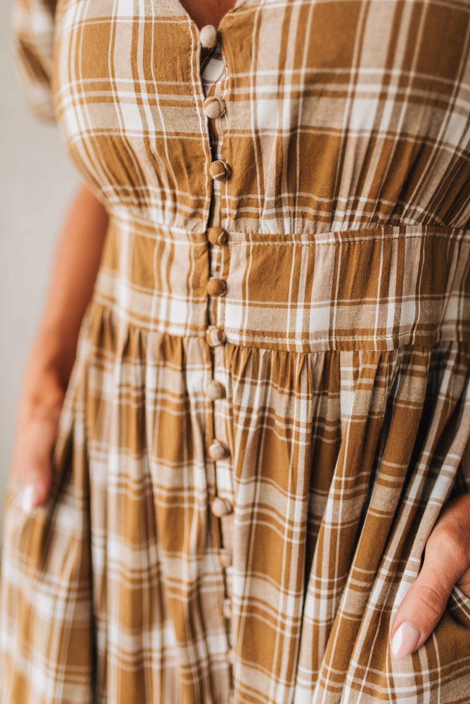Brown plaid dress with buttons on a neutral background