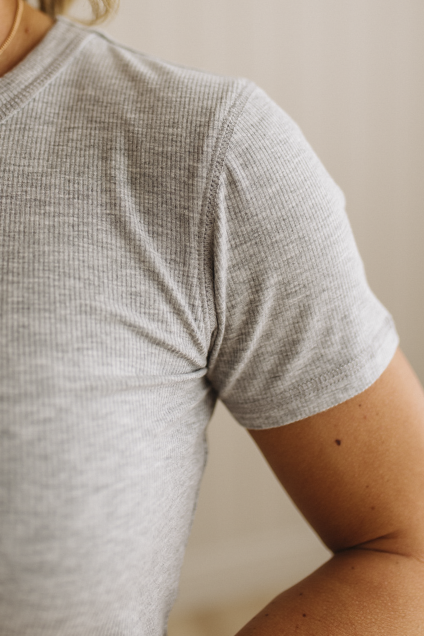 Close-up of a person wearing a gray textured t-shirt against a neutral background