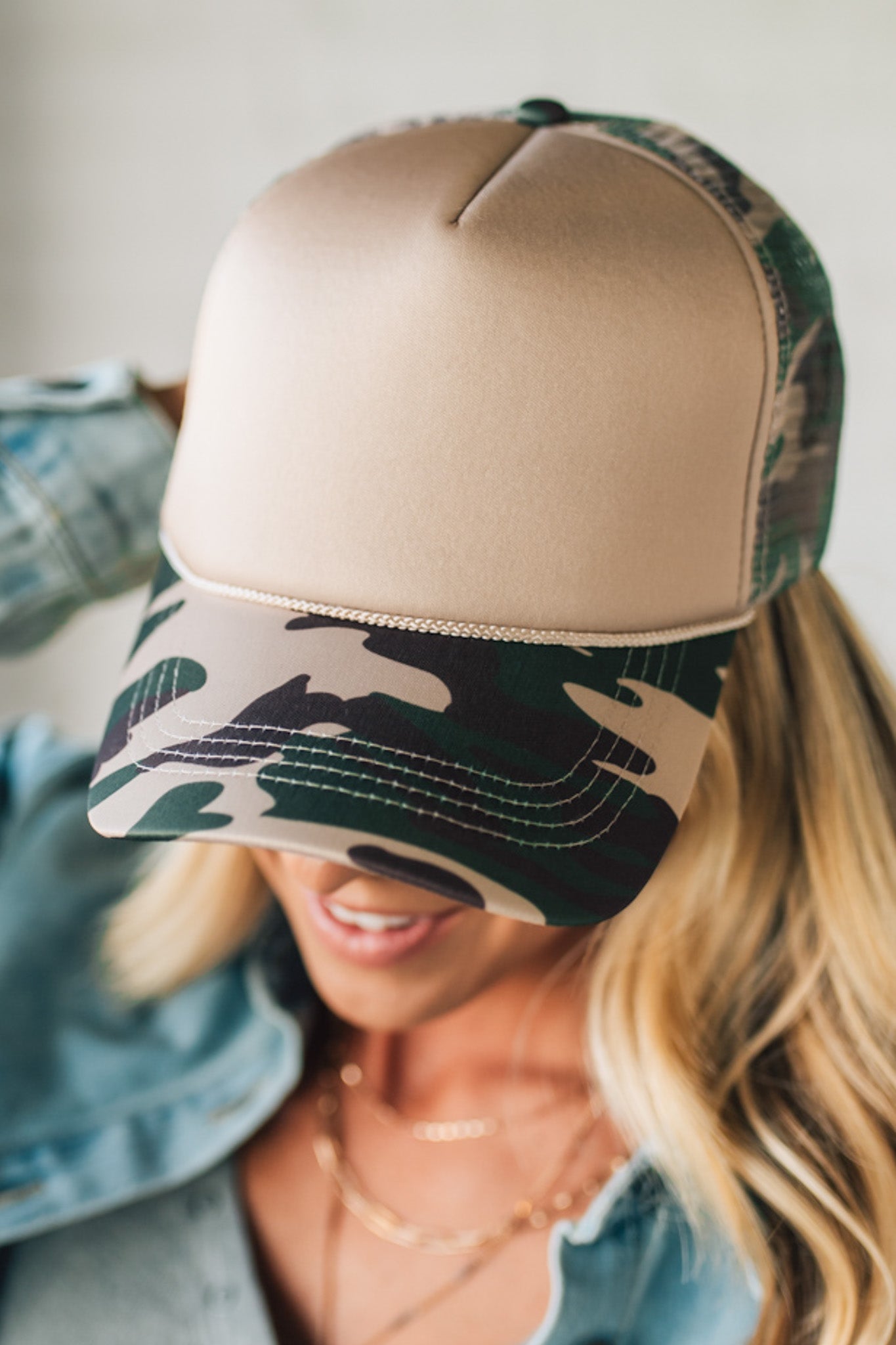 Beige and camouflage baseball cap worn by a person with a blurred background