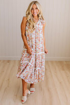 Woman wearing a floral dress standing on a wooden floor with a white wall background