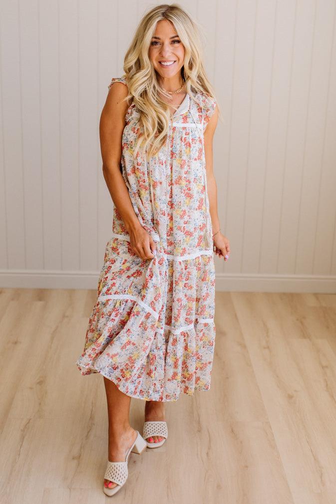 Woman wearing a floral dress standing on a wooden floor with a white wall background