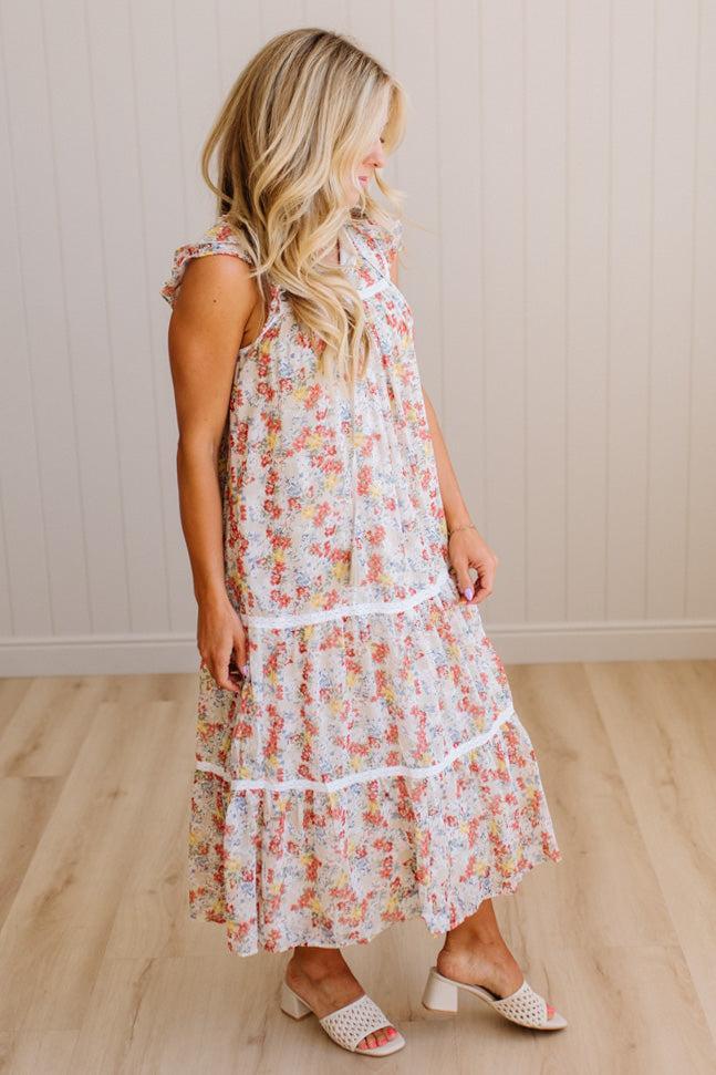 Woman wearing a floral dress standing against a plain background