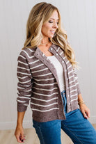 BLONDE WOMAN IN A BRIGHTLY LIT STUDIO WEARING A CREAM TANK AND DARK JEANS SHOWING A OUTSEAMED, LONG SLEEVE, FUZZY, CREW NECK STRIPED BUTTON DOWN SWEATER CARDIGAN IN CHOCOLATE MOCHA.