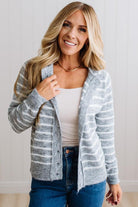 BLONDE WOMAN IN A BRIGHTLY LIT STUDIO WEARING A CREAM TANK AND DARK JEANS SHOWING A OUTSEAMED, LONG SLEEVE, FUZZY, CREW NECK STRIPED BUTTON DOWN SWEATER CARDIGAN IN HEATHER GREY.
