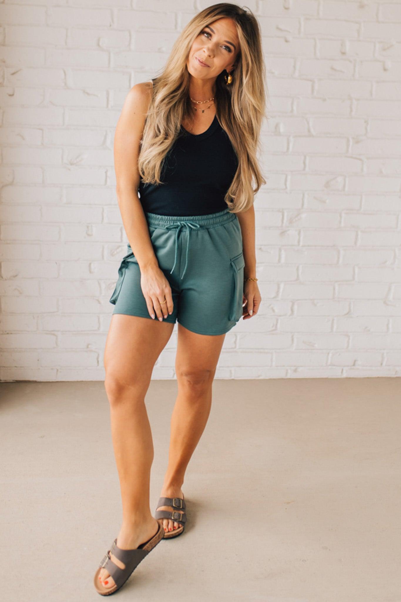 BLONDE WOMAN WEARING SCUBA THIGH POCKET SHORTS WITH ELASTIC WAIST & DRAWSTRING. 